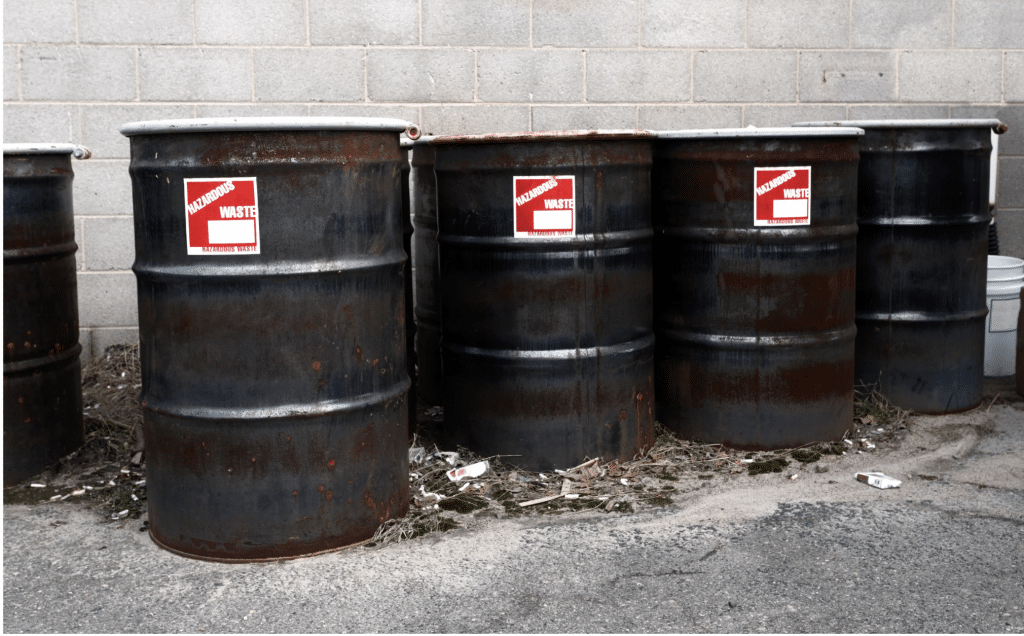 Flammable hazardous waste drums staged outside a facility for certified pickup and transport
