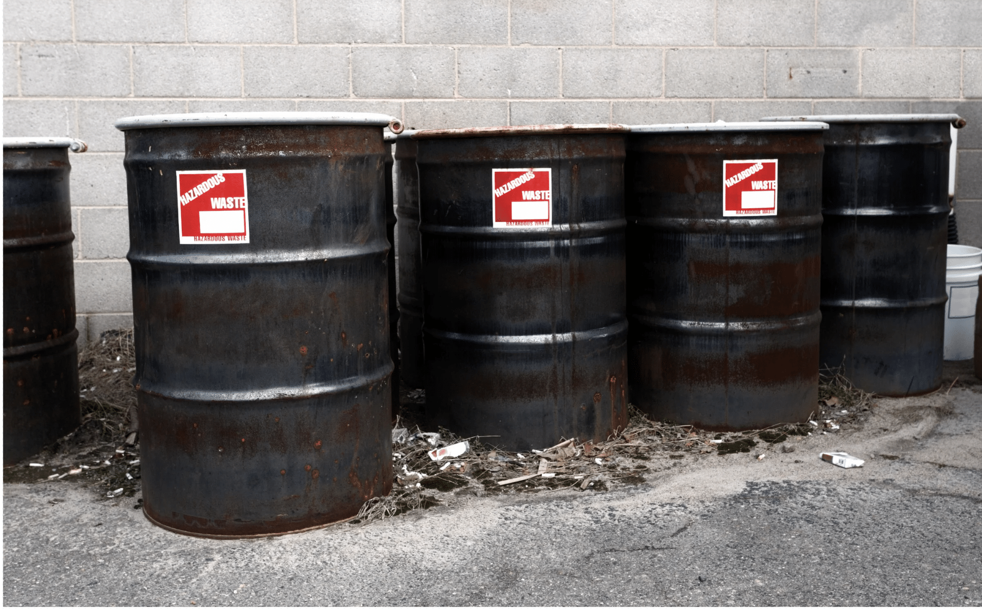 Flammable hazardous waste drums staged outside a facility for certified pickup and transport